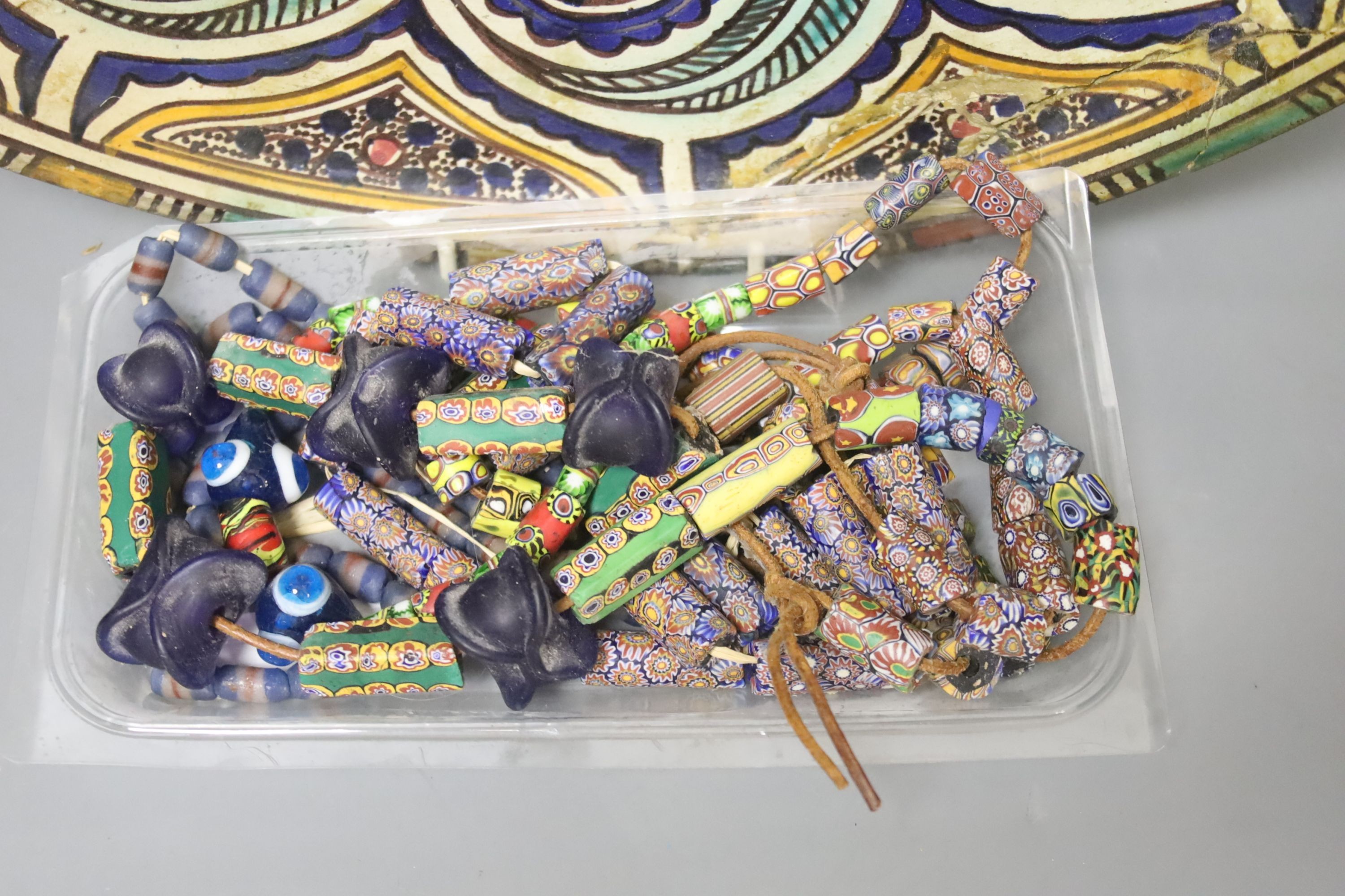 A decorative Moroccan pottery dish and a quantity of Middle Eastern glass beads and 10 turned wooden plates by P D Spear 39cm